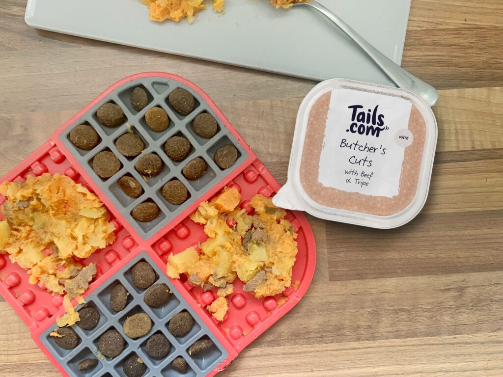 LickiMat slomo filled with tailor-made kibble, mashed sweet potato and swede, and a tails.com wet food tray to the side